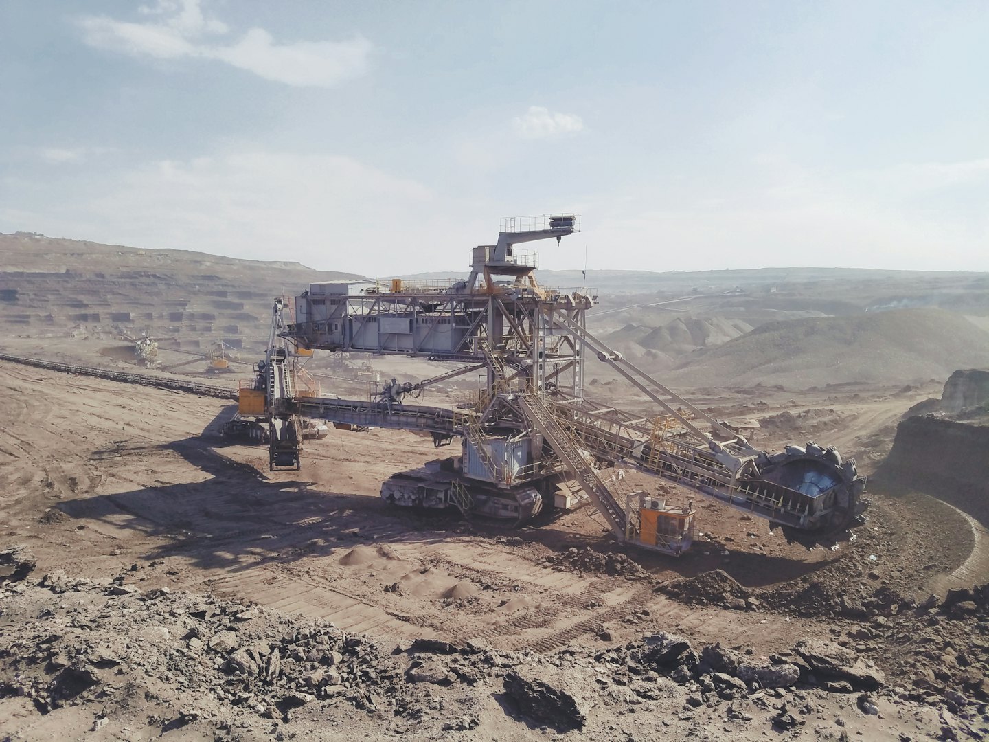 A large bucket-wheel excavator digs earth in an open-pit mine.